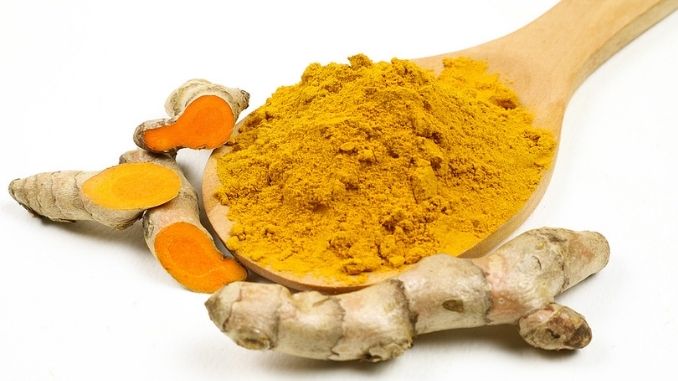 Turmeric powder in wooden spoons