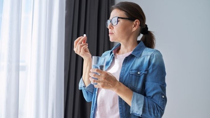 holding pill and glass of fresh water