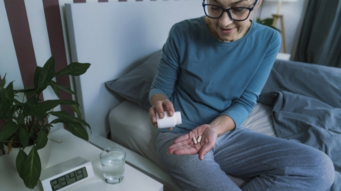 woman-taking-supplement-pill-bed