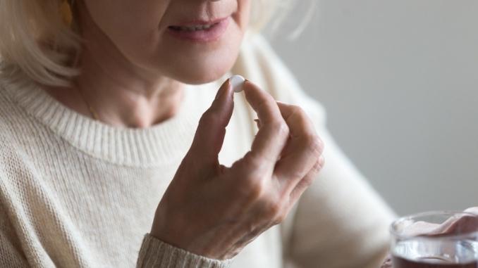 woman-holding-pill-glass-water